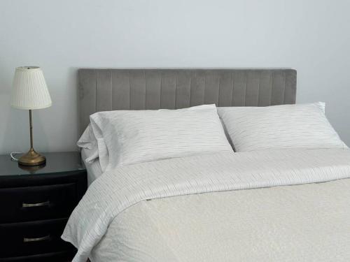 una cama con sábanas blancas y una lámpara sobre una mesa en 1BR City Apt-Parking&View& Homey en Canberra