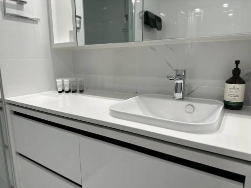 a white bathroom with a sink and a mirror at 1BR City Apt-Parking&View& Homey in Canberra