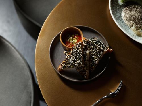 a plate of food on a table with a bowl of food at The Porter House Hotel Sydney - MGallery in Sydney