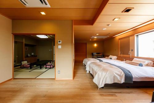 a hospital room with three beds and a desk at Tachibana Shikitei in Kaga