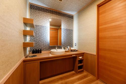 a bathroom with a sink and a mirror at Tachibana Shikitei in Kaga