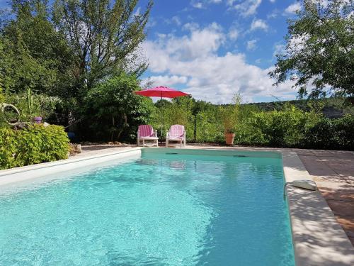 a swimming pool with two chairs and an umbrella at Stylish holiday home near St Br s in Saint-Brès