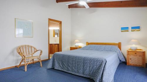 a bedroom with a bed and a chair and a window at Unit 5 of 11 Beach Street Merimbula in Merimbula