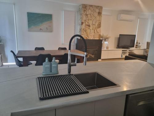 a kitchen counter with a sink and a kitchen with a table at Sand Dunes in Point Lonsdale