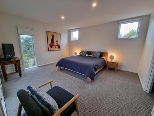 a bedroom with a bed and a tv and windows at Sand Dunes in Point Lonsdale