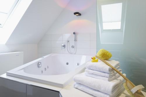 a white bathroom with a tub and a stack of towels at Sorell Hotel Rütli in Zürich