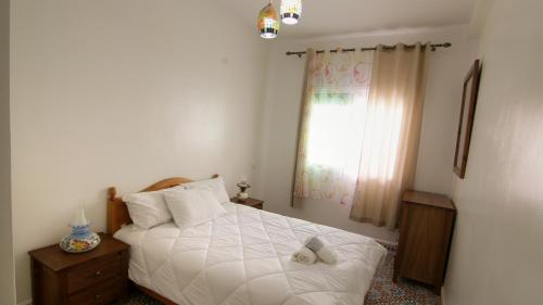 a bedroom with a white bed and a window at zina surf house in Oualidia
