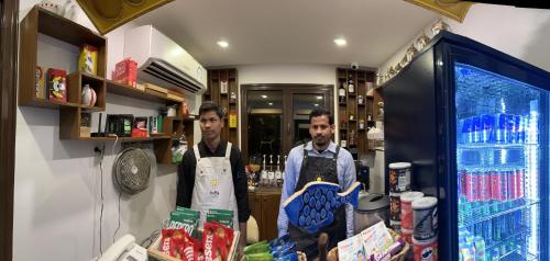 two men wearing aprons standing in a kitchen at منتجع اووه يامال البحري في الخيران OOh Yaa Mal in Al Khīrān