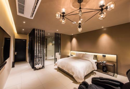 Schlafzimmer mit einem Bett und einem Kronleuchter in der Unterkunft Le Stendal Hotel in Daejeon