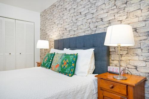 a bedroom with a white bed and a stone wall at Accueil Chez Francois in Montréal