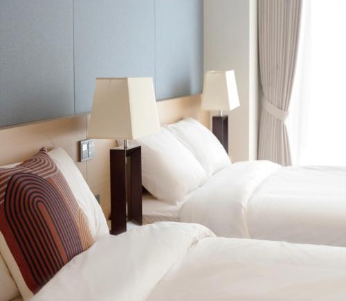 two beds in a hotel room with two lamps at C-One Resort Jaeundo in Sinan