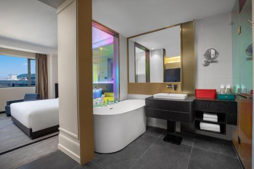 Wingate By Wyndham Wuhan Optics Valley في ووهان: حمام به سرير وحوض استحمام ومغسلة
