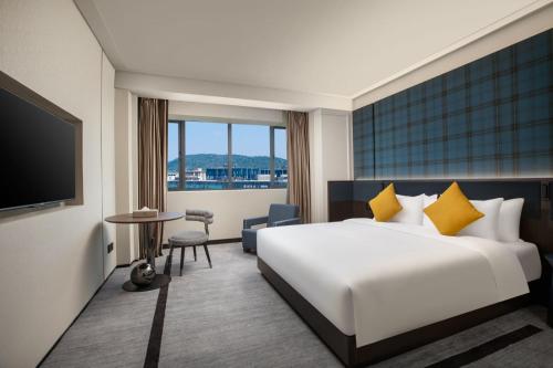 una camera d'albergo con letto e TV di Wingate By Wyndham Wuhan Optics Valley a Wuhan