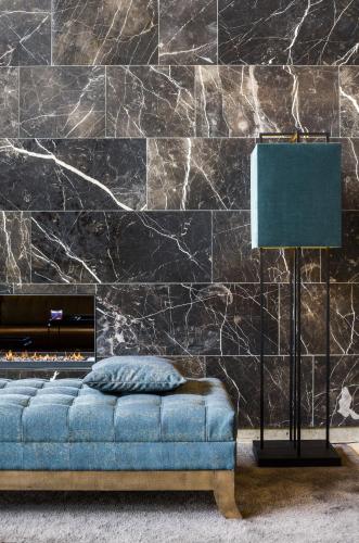 a living room with a blue couch and a stone wall at Van Der Valk Hotel Zwolle in Zwolle