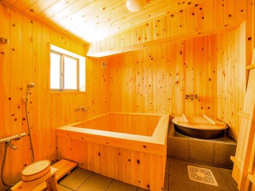 baño de madera con bañera y lavamanos en Chikubu Yuuan en Nagahama