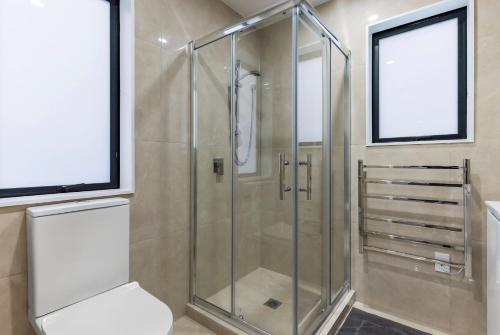 a glass shower stall in a bathroom with a toilet at Jupiter St Holiday Home No 3 in Auckland