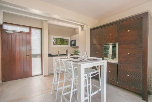 a kitchen with a white table and white stools at Villa Maorie 5 chambres avec piscine privée in Le François