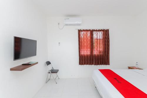 a white room with a bed and a television at RedDoorz near RSUD Banten Serang in Banjar