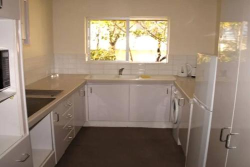 a white kitchen with a sink and a window at Kundu Lodge - Hosted by Burleigh Letting in Gold Coast
