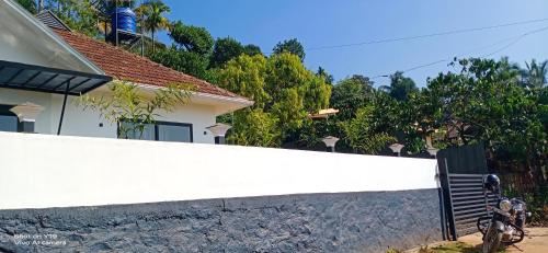 a white fence in front of a house at Teaside Inns in Vythiri