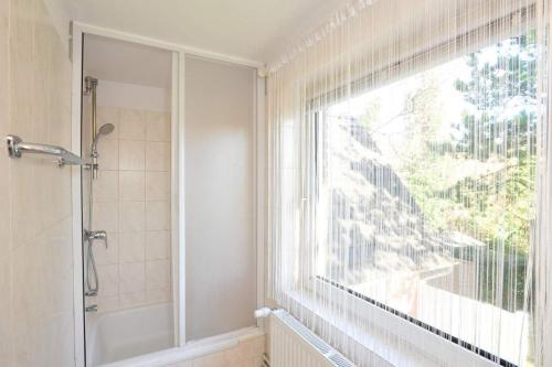 La salle de bains est pourvue d'une douche et d'une grande fenêtre. dans l'établissement Haushaelfte-Kuddel-104, à Sankt Peter-Ording