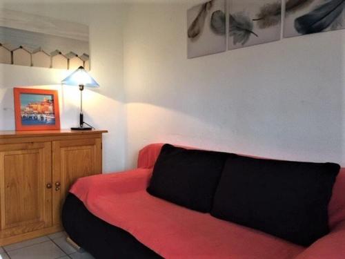 uma sala de estar com um sofá vermelho e um candeeiro em Maison Gruissan, 1 pièce, 4 personnes - FR-1-229-831 em Gruissan