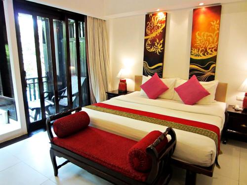 1 dormitorio con 1 cama grande y un banco rojo en Yantarasri Resort, en Chiang Mai