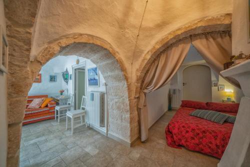 a bedroom with a red bed and a living room at Trulli di Puglia - Casa vacanze in Valle d'Itria in Martina Franca