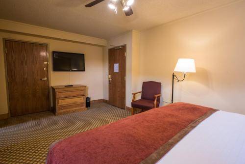 a hotel room with a bed and a chair and a television at The Grand Lodge Hotel and Suites in Mount Crested Butte