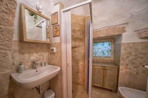 a bathroom with a sink and a toilet and a mirror at Trulli di Puglia - Casa vacanze in Valle d'Itria in Martina Franca