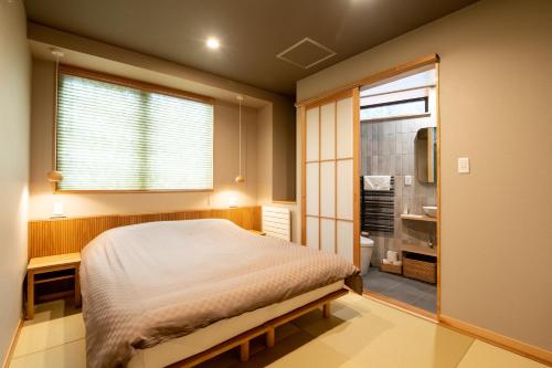 a bedroom with a large bed and a bathroom at Tanuki Nozawa in Nozawa Onsen