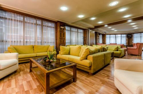 a living room with yellow couches and a table at Hotel Princess in Ourense