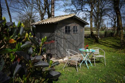une table et des chaises devant un petit hangar dans l'établissement Vacances aux Petites Rivières, à Saint-Loup-de-Saintonge