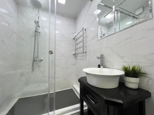 La salle de bains blanche est pourvue d'un lavabo et d'une douche. dans l'établissement Студия в скандинавском стиле, à Pavlodar