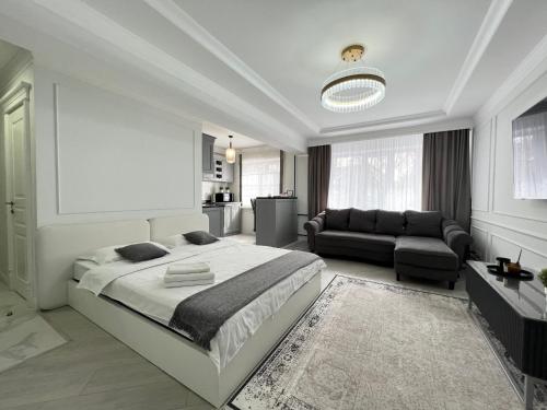 a white bedroom with a bed and a couch at Студия в скандинавском стиле in Pavlodar