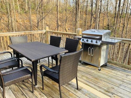 a grill on a deck with a table and chairs at Spectacular Log Cabin Home 45 minutes to Asheville in Marion