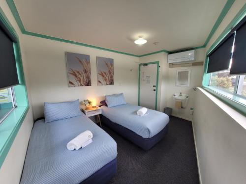 a small room with two beds and a bathroom at Pacific Coast Lodge and Backpackers in Mount Maunganui