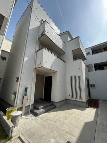 a large white building with a door and stairs at ALL TRUST2馆临近心斋桥道頓堀难波直达梅田关西机场Usj全新独栋别墅四个卧室可住8人超大空间3卫2浴厨房设施齐全电视冰箱洗衣机空调配置齐全免费停车4分钟步行至今宫站 in Osaka