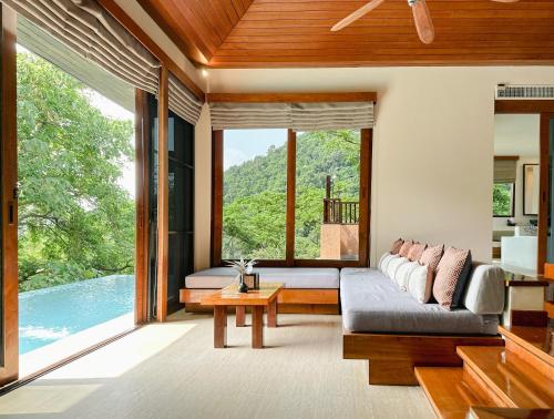 a living room with a couch and a large window at Korsiri Pool Villas in Panwa Beach