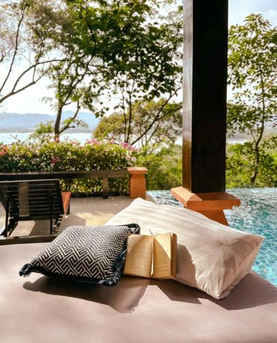 a bed with two pillows and a book on it at Korsiri Pool Villas in Panwa Beach