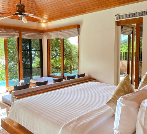 a bedroom with a large bed and large windows at Korsiri Pool Villas in Panwa Beach