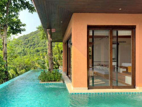 a villa with a swimming pool and a bedroom at Korsiri Pool Villas in Panwa Beach