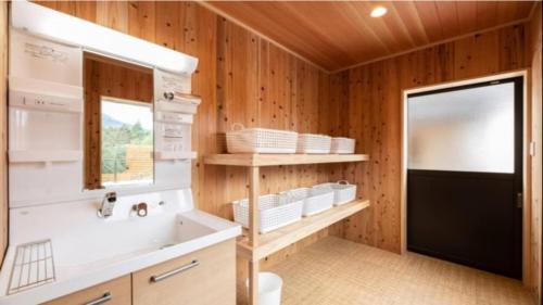 a bathroom with wooden walls and a sink and a mirror at YUFUIN O-YADO YUKI ONSEN in Yufu