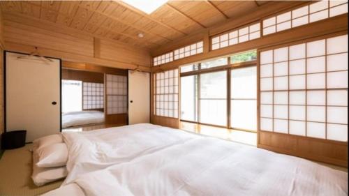 a bedroom with a large white bed with windows at YUFUIN O-YADO YUKI ONSEN in Yufuin