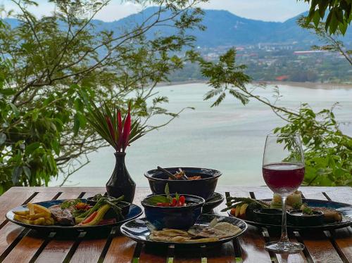 a table with plates of food and a glass of wine at Korsiri Pool Villas in Panwa Beach