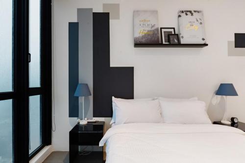 a bedroom with a bed with white sheets and blue accents at EST KL Sentral Bangsar Kuala Lumpur in Kuala Lumpur