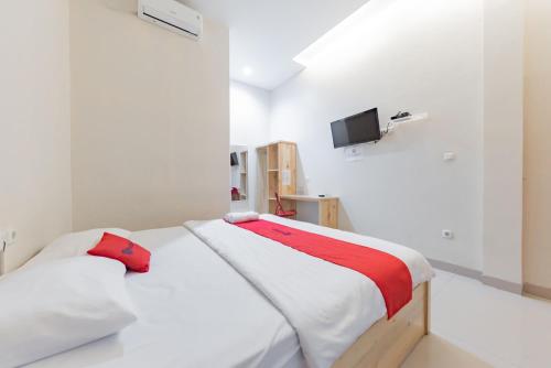 a white bedroom with a bed and a tv at RedDoorz Syariah near DPRD Kabupaten Subang in Subang