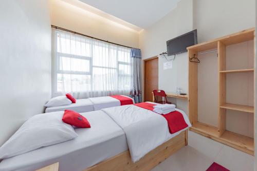 1 dormitorio con 2 camas y TV. en RedDoorz Syariah near DPRD Kabupaten Subang, en Subang