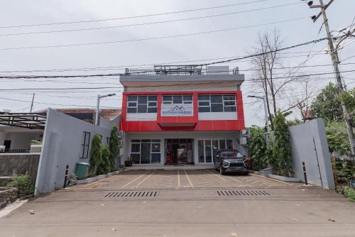 a red building with a car parked in a parking lot at RedDoorz Syariah near DPRD Kabupaten Subang in Subang