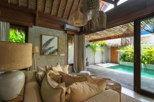 a living room with a couch and a swimming pool at Amaka Villas in Uluwatu